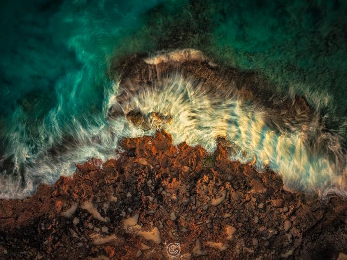 Foto aérea de sedas de agua sobre roca erosionada en Cap de Salines, Mallorca — un segundo de exposición al atardecer