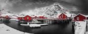 Winter panorama of Å, the last village in Lofoten, with red cabins facing the icy sea and snowy mountains in the background